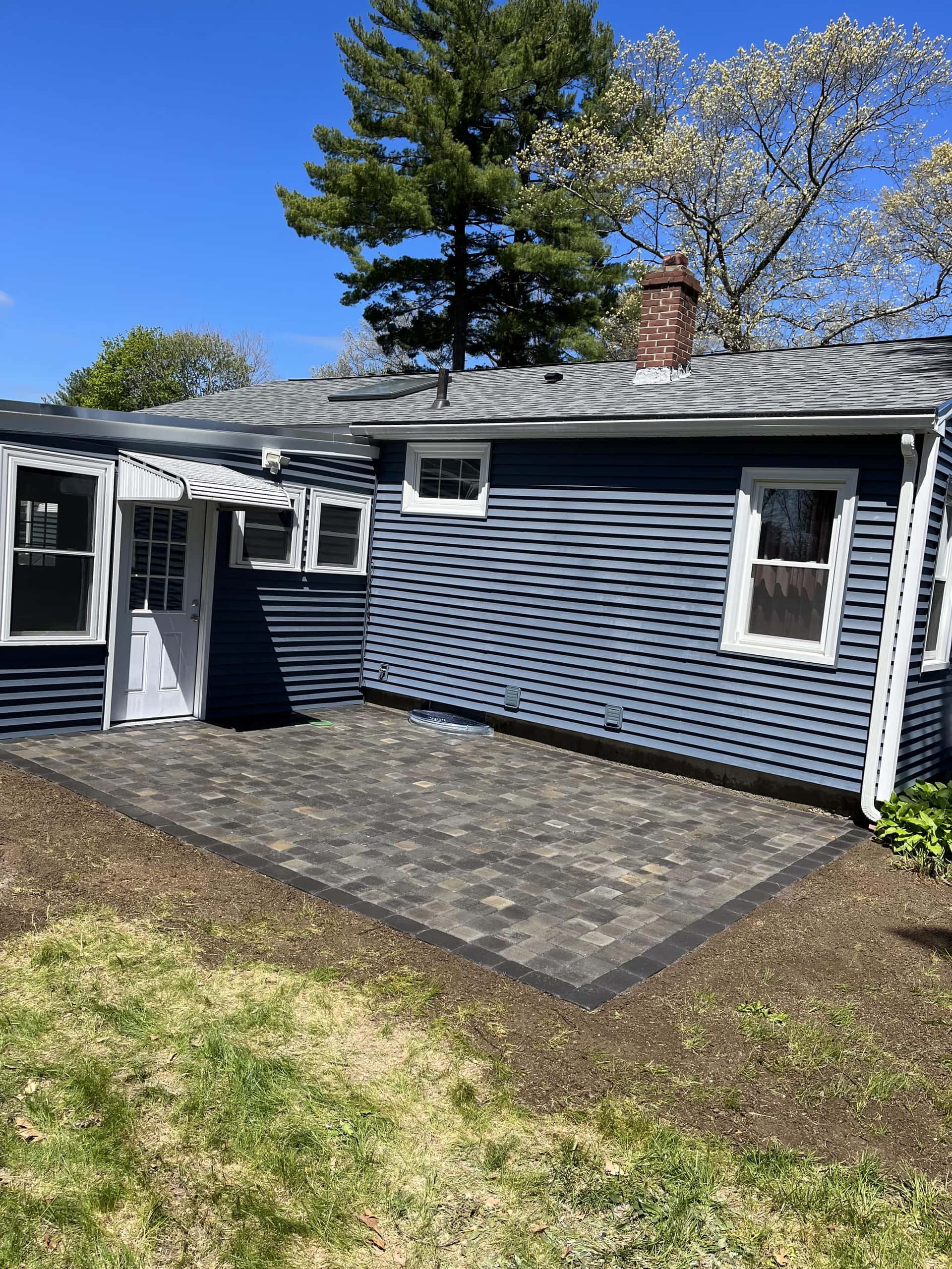 Paver patio installed around a home in Hudson, MA by YellowStone Masonry Group